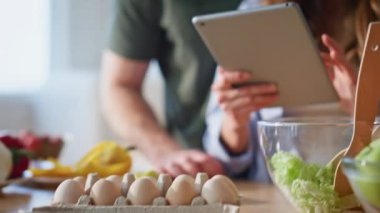 Apartman mutfağında tablet arama tarifi kullanan sevgililer. Tatlı eş, yakışıklı koca dijital bilgisayarda gezinip ne pişireceğini düşünüyor. Rahatlamış aşıklar mutfakta yemek yapıyor. 