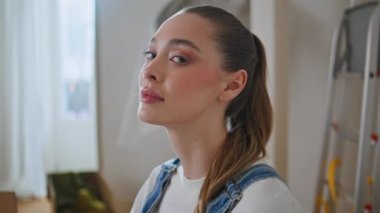 Yeni daireye poz veren güzel bir kadın sakince kameraya bakıyor. Oturma odasında merdivende oturan, beyaz tişört giyen rahat kadın portresi. Çekici kız milenyum sıcacık hafta sonunun tadını çıkar