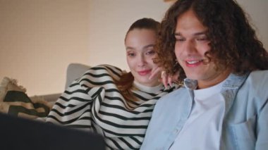 Harika bir çift dizüstü bilgisayar seyrediyor. Karanlık daire kanepesinde birlikte dinleniyorlar. Rahat eşler kanepede online alışveriş yapan bilgisayarları tartışıyor. Mutlu ruh eşleri web sitesi evde geziniyor.