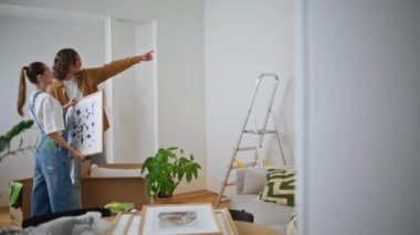 Duvardaki oturma odasını seçen bir çift. Kocası çerçeveli sanat eserleri taşıyan bir kadının evini dekore etmeye yardım ediyor. Mutlu taşınan eşler, resimlerin parlak ev ortamında yerleştirilmesini tartışıyor..