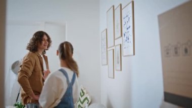 Bir çift yeni evdeki yenileme planlarını tartışıyor. Esmer, modern sanat eserlerini beyaz duvara asarak şık bir iç dekorasyon yaratıyor. Sevgili eşler öpüşürken rahat bir apartman atmosferinin tadını çıkarın..