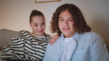 Çift dizüstü bilgisayarla oyun seyrediyor rahat oturma odasında oturuyorlar. Rahatlamış eşler karanlık akşam evinde bilgisayar ekranına bakıyor. Mutlu aile web sitesi sosyal medyası dairede.