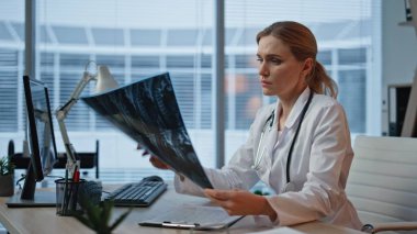 Radyolog hasta taramasını kontrol ediyor. Muayenehanede röntgen analizi yapan ciddi bir pratisyen. Radyoloji resminde çalışan düşünceli kadın uzman.