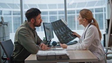 Mutlu hasta muayenehanede el sıkışıyor. Kapanışta gülümseyen doktor klinikteki adamla başarılı tedavi terapilerini tartışıyor. Röntgen çeken sağlık uzmanı rehabilitasyon sonuçlarının keyfini çıkarıyor.