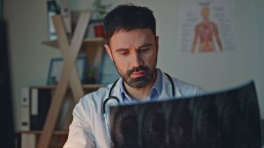 Tıbbi uzman röntgen görüntülerini kontrol ediyor. Hastanede gece vardiyasında çalışan yorgun adam doktor. Tarama teşhisini analiz eden düşünceli bir pratisyen. Stresli sağlık çalışanı.
