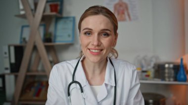 Pov pratisyen hekimi, tıbbi ofiste online danışmanlık yapıyor. Yakın çekim doktoru, klinikte sağlık tedavisi ile ilgili video görüşmesinde konuşuyor. Gülümseyen kadın doktor test sonuçlarını akşam odasında tartışıyor..