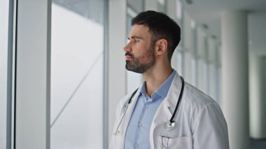 Düşünceli cerrah pencereye yakından bakıyor. Düşünceli bir sağlık hizmetleri uzmanı içeride çözümü yansıtıyor. Steteskop düşünme hastalıkları konusunda uzman bir doktor. Hastane personeli..