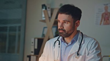 Gece kliniğinde gözlerini ovuşturmaktan yorgun düşmüş bir doktor. Hastanede akşam vardiyasında çalışan yakın doktor daktilo bilgisayarı. Stresli sağlık çalışanı kahve içiyor internette tıbbi kayıtları kontrol ediyor..