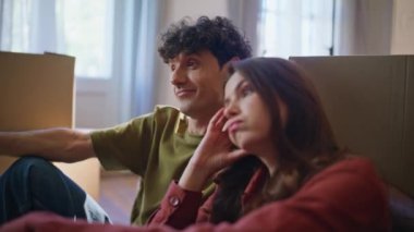 Yorgun çiftin taşınma stresi yakın çekim hissi. Oturma odasında karton kutulara bakan yorgun ve evli bir çift. Yorgun genç aile yeni ipotek evinde dinleniyor. Emlak yatırımı 