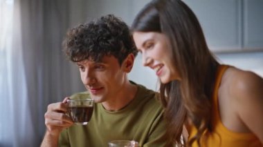 Sabah çifti birlikte kahve içerken dizüstü bilgisayarı yakından izliyorlar. Genç eşler ilginç bir televizyon programı izliyorlar. Mutfak dairesinde kahvaltı ediyorlar. Kıvırcık adam gülümseyen kadın hafta sonu vakit geçiriyor