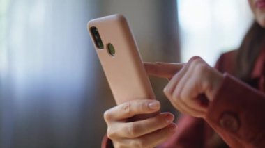 Evdeki akıllı telefon ekranına dokunan kadın eli. Tanımlanamayan serbest çalışan apartmandaki cep telefonunda sosyal medyada geziniyor. Bilinmeyen kadın oturma odasında cep telefonuyla mesaj açıyor.