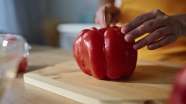 Mutfağı yakın plan keserken el yapımı dolma biber dilimleme. Meçhul kadın, apartman mutfağında bıçakla taze vitamin malzemeleri hazırlıyor. Bayan öğle yemeği için sağlıklı sebze kesiyor. 