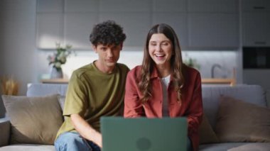 Gülümseyen çift, oturma odasını kapatıyor. Mutlu ruh eşleri diz üstü bilgisayara el sallıyor rahat koltukta dinleniyorlar. Olumlu evli çiftler evlerinde dostça buluşmanın keyfini çıkarırlar.