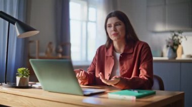 İnternette konuşan gülümseyen kız dizüstü bilgisayarın internet kamerasıyla toplantı yapıyor. Mutlu kadın videosu oturma odasındaki masadan arayıp hafta sonu dinleniyor. Neşeli serbest yazar dostça uzaktan iletişimin keyfini çıkar. 