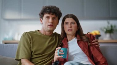 Aile çifti, kanepede birlikte gerilim filmi izliyorlar. Oturma odasındaki rahat koltukta gergin film anından korkan odaklanmış kadın ve erkek. Gülümseyen eşler hafta sonlarında TV dehşetinden hoşlanırlar