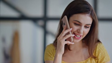 Güzel bir bayan cep telefonunu arıyor ve gülümsüyor. Mutlu kadın, iş yerinde kağıtlarla çalışan dostane bir cep telefonu sohbeti yapıyor. Ofiste akıllı telefondan konuşan güzel iş kadını..