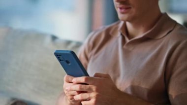 Sakin bir adamın cep telefonuna mesaj atması rahat bir oturma odasında oturması. Rahat evdeki internet iletişimi için akıllı telefonu kullanan rahat bir adam. Erkek portresi cep telefonuyla kapalı alanda etkileşime giriyor