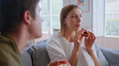 İki genç, sabahleyin evde pizza yiyip film izliyorlar. Gülümseyen genç çift rahat koltuklarda rahatlıyor. Mutlu aile TV şovundan zevk alıyor. Evde eğleniyor. 