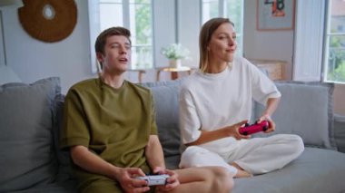 Video oyunu oynayan gençler birlikte kanepede oturuyorlar. Heyecanlı sevgili oyunu kazanmaya çalışıyor. Gergin hissediyorum. Evde elinde joystick tutan aktif bir kadın video oyunu yarışmasından zevk alıyor