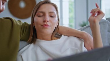 Hafta sonu ev kapanışı sırasında internetten çiftlere sarılma planlama gezisi. Neşeli romantik kız arkadaş bir sonraki hedef tablet için fikir üretiyor. Neşeli bir kadın el kol hareketleriyle koltukta oturuyor. 