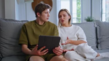 Gençler evdeki kanepede oturup internet üzerinden toplantı yapıyorlar. Gülümseyen genç bir çift kanepedeki bilgisayar kamerasını arıyor. Mutlu romantik çift dairede uzaktan iletişimin keyfini çıkar. 