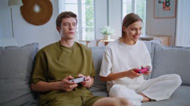 Gülümseyen oyuncular oturma odasındaki video oyunlarından hoşlanırlar. Çevrimiçi video oyunu oynayan mutlu çift konsollarda düğmelere basıyor. Neşeli aile birlikte yarışıyor Sevinç heyecanı hissederek 