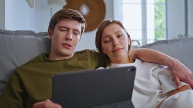 Modern evlerde tablet bilgisayarı arayan rahat gençler. Oturma odasındaki koltukta dijital cihaz kullanan sakin bir çift. Mutlu gençler evde birlikte vakit geçiriyorlar. 