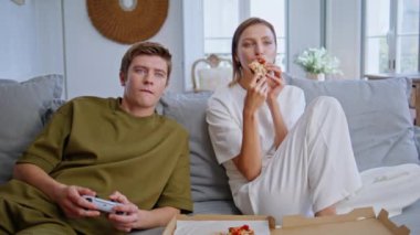 Kanka aşıklar birlikte kanepede oturup konsol oynuyorlar. Evde pizza yiyen genç bir kadın erkek arkadaş oyunu seyrediyor. Gençler hafta sonunun tadını çıkarıyor. Gülümseyen adam elinde joystickle kızla vakit geçiriyor.