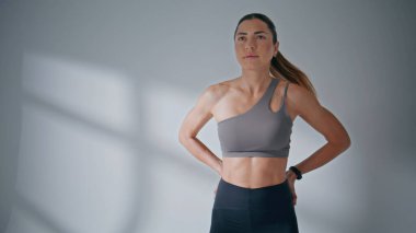 Stüdyoda direniş bandıyla bacakları üzerinde çömelmiş bir kadın. Beyaz duvar arka planında spor yapan bir bayan sporcu. Spor kıyafetli pozitif bir kız tek başına egzersiz yapıyor. 