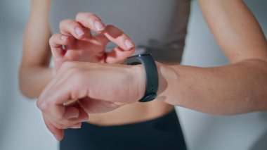 Eller akıllı saate yakından dokunuyor. Sporcu egzersiz sırasında ekrandaki performans verilerini kontrol eder. Tanınmayan sporcu kadın bileğine bant takıyor. Kapalı alan aktivite fitness eğitimi 