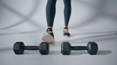 Bilinmeyen sporcu, beyaz odada dambıl alıyor. Fitness kadın vücudu ağırlık çalışması yapmaya başladı. Tanımlanamayan bir kadın kaslarını geliştiriyor. Spor insanları konsepti