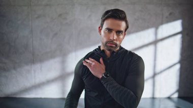 Ciddi bir sporcu stüdyo resminde omuzlarını ısıtıyor. Spor giyim sektöründeki atletik adam sıkı çalışmaya hazırlanıyor. Spor yapan adam sabah rutininin tadını çıkarıyor. Esmer, içeride egzersiz yapıyor. 