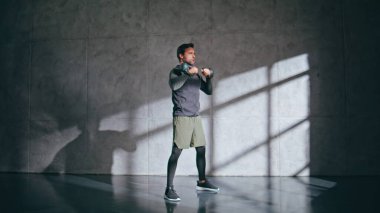 Güçlü vücut geliştirici, beden dersinde çömelme çanı kaldırıyor. Kilolu sağlıklı bir adam antrenmanından zevk alıyor. Fitness elemanı kas gücü için ağır ekipman tutuyor. Vücut geliştirme ve ağırlık kaldırma 