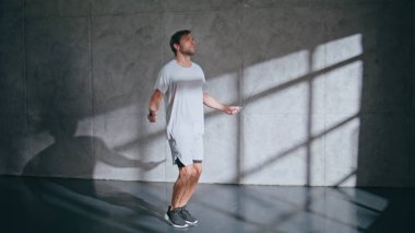 Güçlü adam çatı katında atlama halatıyla kardiyo çalışması yapıyor. Spor kulübünde spor antrenmanı sırasında ip atlayan aktif bir sporcu. Boş spor salonunda egzersiz yapan zinde bir adam.