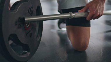 Yakından sporcu elleri spor salonunda halterin üzerine ağır tabaklar koydu. Güçlü sporcu ağırlık kaldırma antrenmanına hazırlanıyor. Erkek sporcu spor malzemelerini egzersiz için hazırlıyor 