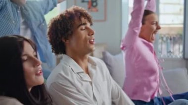 Oturma odasındaki kanepede video oyunu oynayan heyecanlı gençler. Hevesli arkadaşlar hafta sonu hafif dairede toplanıp rekabetin tadını çıkarıyorlar. Hüsrana uğramış kıvırcık ergen oyunu kaybediyor.