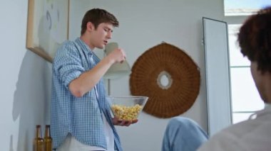 Oturma odasındaki partide atıştırmalık yiyen genç adam. Genç adam arkadaşlarıyla takılıyor ve bilinmeyen kıvırcık çocukla konuşuyor. Milenyum insanı evinde arkadaşlarıyla eğleniyor. İnsan yaşam tarzı