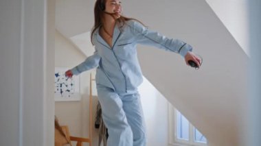 Sabahları yatakta zıplayan heyecanlı bir kadın. Pijamalarıyla dans eden mutlu güzel kız enerjik müzik listesine geçiyor. Neşeli ince model yalnız zaman geçirmenin keyfini çıkarıyor. Gülümseyen kadın özgürlüğü kutluyor 