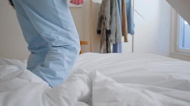 Güneş ışığında pijama bacakları yatak odasına atlıyor. Enerjik neşeli kadın favori müziği dinliyor yumuşak yatakta dans ediyor. Heyecanlı genç kız dairede özgürce eğleniyor.