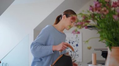 Mutfak tezgahında çay hazırlayan güzel bir kız. Güzel bir kadın çaydanlıktan bardağa su dolduruyor. Genç bayan kahvaltısını evde yapıyor. Sakin manken tavan arasında tek başına içki fincanı alıyor.