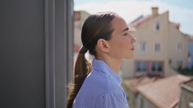 Mutlu bayan yaz rüzgarının tadını çıkarıyor. Balkonda, yan portrede. Şehre bakan şehvetli bir kadın şehir manzarası terasına yakından bakıyor. Güneşin altında siesta yapan güzel, rahat kız.