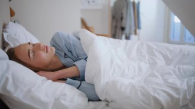 Mutlu bayan uyandı yatak odası kapanıyor. Sağlıklı bir kadın rahat bir yatakta ellerini uzatıyor. Mavi pijamalı kaygısız kız yatağında tek başına yatıyor. Yumuşak yastıkta gülümseyen bir model. Sabah uyanma konsepti