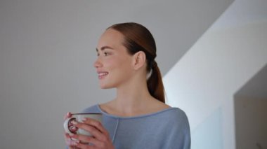 Huzurlu bir kadın sabah güneş ışığında çay fincanı içiyor. Hayalperest kız tavan arasında cappuccino içerken hayatın tadını çıkardığını düşünüyor. Gülümseyen kadın bir yudum alıyor ve içerideki fotoğrafa bakıyor. 