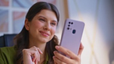 Akıllı telefondan haber izleyen bir kadın yakın çekimde online içerikten keyif alıyor. Gülümseyen iş kadını şirket ofisindeki cep telefonu mesajında iyi haberler okuyor. İnternet siparişi veren mutlu müşteri.
