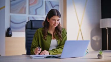 Modern kreatif acentede çalışan başarılı bir kadın. Gülümseyen iş kadını bilgisayarda klavye yazıp not alıyor. Şirketin işyerinde kendine güvenen esmer geliştirme projesi.