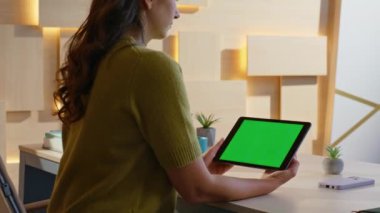 Modern iş yerindeki Chroma Key tabletindeki Webinar 'ı izleyen çalışan yakınlaş. Kadın yönetici ofisteki yeşil ekranlı bilgisayara bakıyor. İş kadını elleri kapalı mekanda dijital cihaz tutuyor