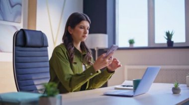 Stresli bayan cep telefonuyla modern şirket işyerinde dizüstü bilgisayarla oturuyor. Sinirli iş kadını akıllı telefondan banka kredisi bildirimi alıyor. Hayal kırıklığına uğramış kadın endişeli telefon mesajı.