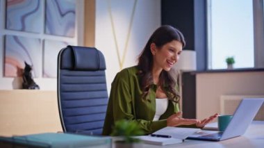 İş kadını, modern ofiste otururken görüntülü aramada selamlıyor. Gülümseyen kadın yönetici çevrimiçi konferansta iş hakkında konuşuyor. Sanal toplantıda bilgiyi açıklayan akıllı çevrimiçi öğretmen.