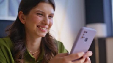 İş kadını, şirketlerin iş yerinde cep telefonuna mesaj atarken elini uzatıyor. Gülümseyen iş kadını modern ofisteki akıllı telefondan mesaj atıyor. Mutlu kadın serbest çalışan içeride cep telefonu kullanarak internette sohbet ediyor..