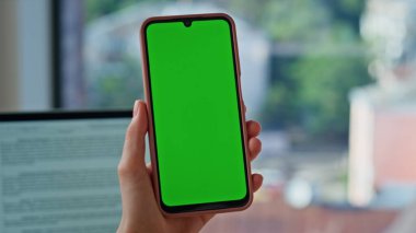 Modern ofis kapanışında el ele tutuşma cep telefonu. Bilinmeyen iş kadını iş yerindeki yeşil ekranlı akıllı telefondan iş mesajı okuyor. Kadın CEO Chroma Key cep telefonunda çevrimiçi tarama uygulaması